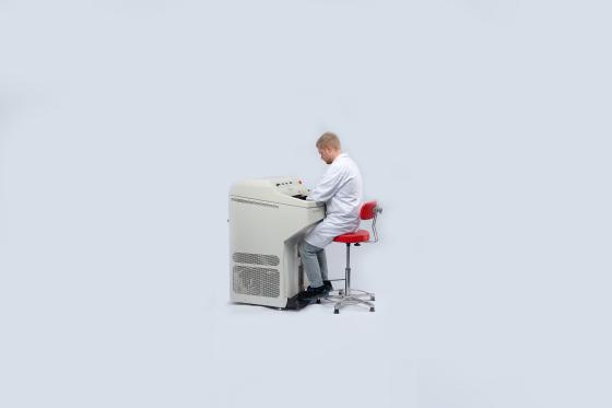 Person in lab coat sitting at a Leica CM1950 cryostat instrument